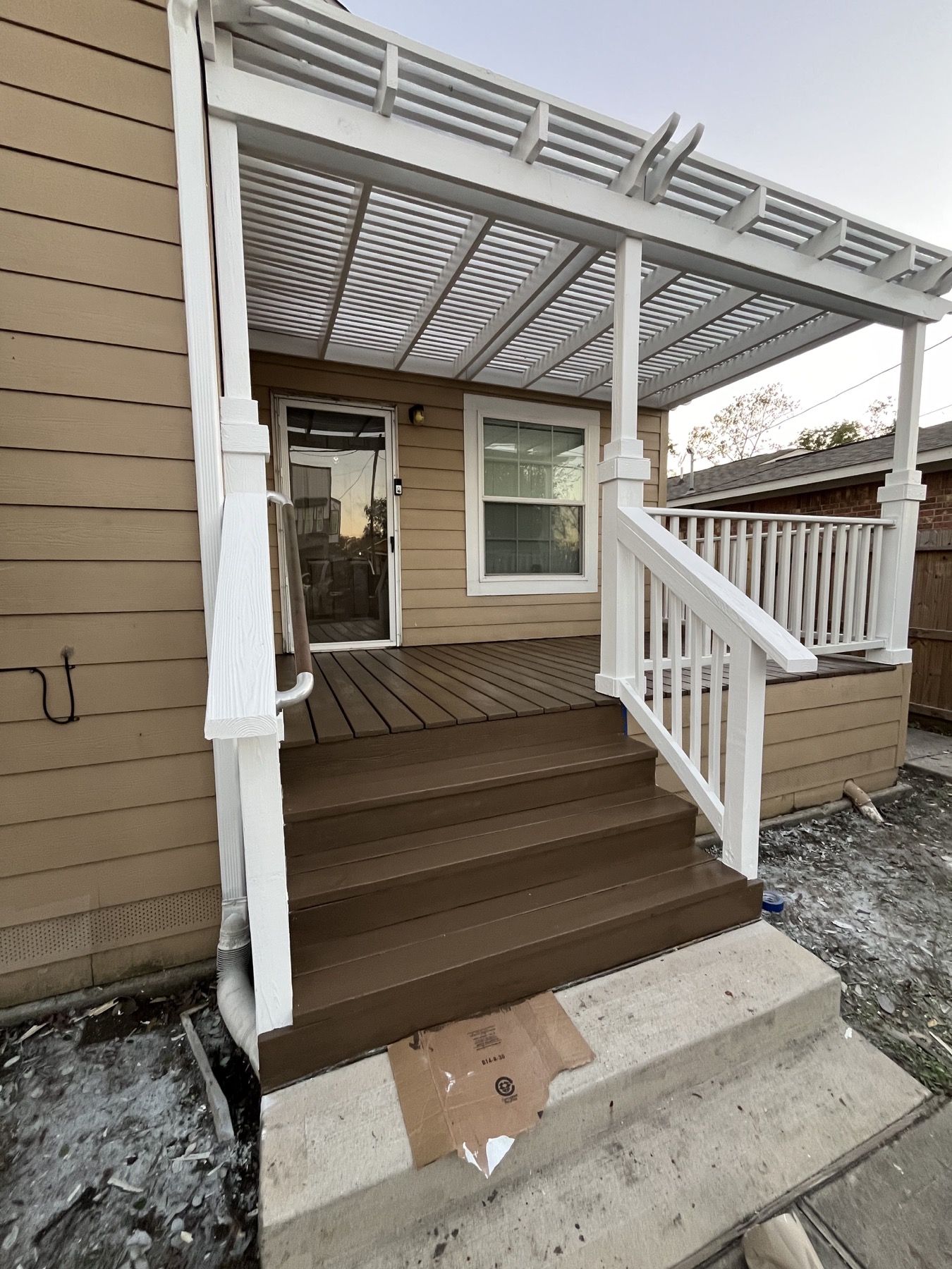 After restoration: complete porch and pergola with freshly painted white beams, posts and railings, and finished brown stairs