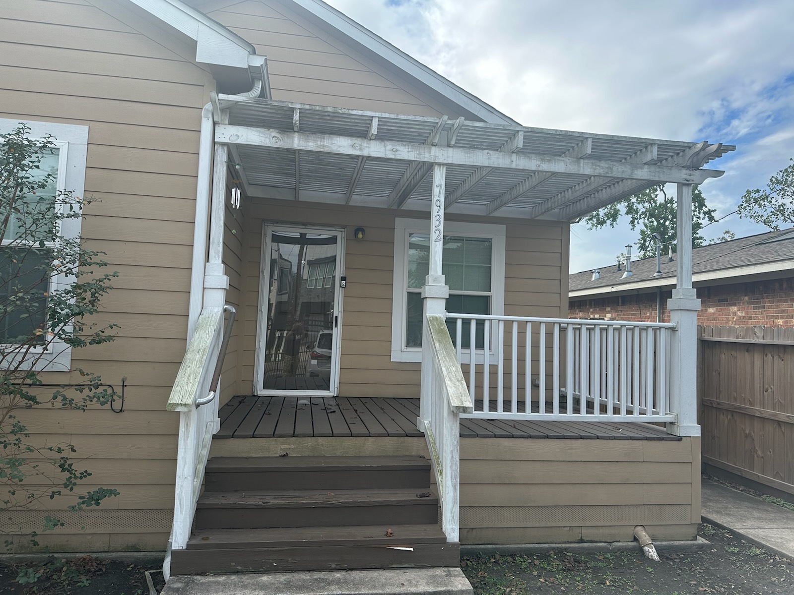 Before restoration: full porch and pergola with weathered white woodwork and worn brown stairs